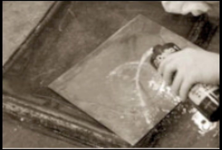 A hand working on a copper plate